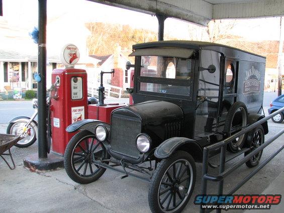 Black vintage truck with "Jack Daniel's" text on the side, parked next to a red gas pump