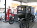 2006 Victory Kingpin - A vintage truck with a boxy rear compartment is parked next to an old gas pump, with a motorcycle visible to the left.