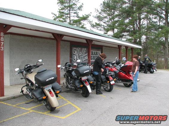 Several motorcycles parked in front of a building with a sign that says 'Half Time Bar & Grill'
