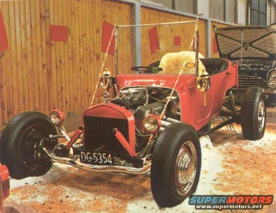 Red hot rod with license plate DG-5354 and exposed engine. Another vehicle is visible behind