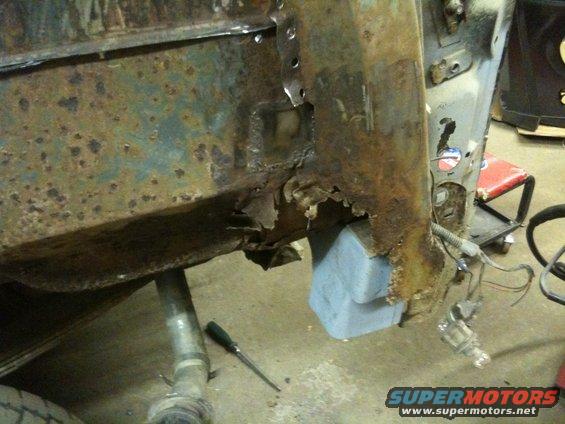 Heavily rusted metal frame of a vehicle, possibly a truck or SUV, with some blue protective material visible