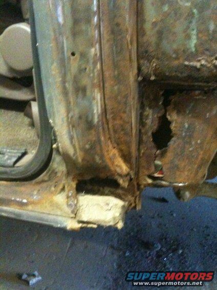 Heavily rusted door frame with large hole