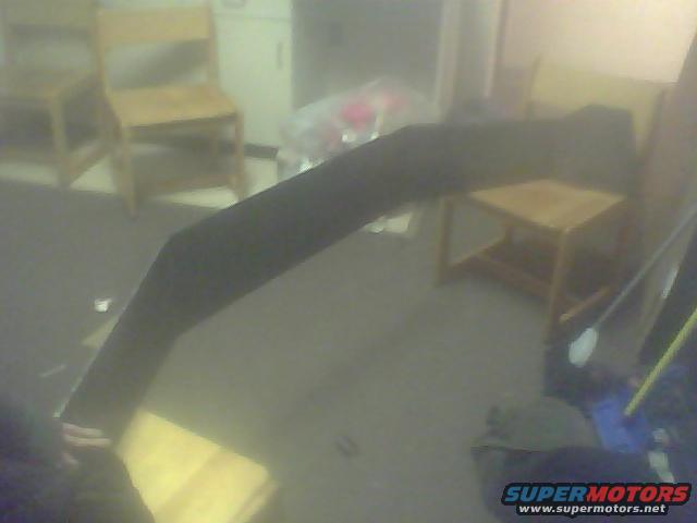 Black curved object, possibly a car part, lying on the floor