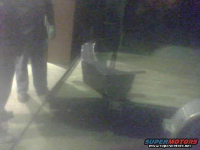 Trailer hitch and wooden bed of a trailer, with two people standing nearby