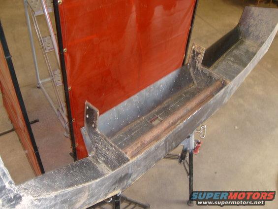 Custom fabricated bumper section on a stand, with a welding screen behind it