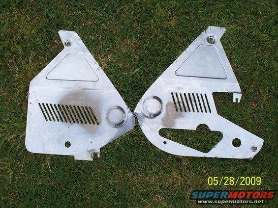Two silver motorcycle side covers with vents and circular cutouts on grass