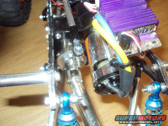 RC car chassis with blue shocks, silver metal parts, and a purple electronic speed controller