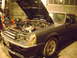 1981 Ford Mustang - A dark gray 1981 Ford Mustang coupe is parked in a garage with its hood open, revealing the engine.
