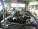 1981 Ford Mustang - Engine hoist lowering a V8 engine into a car's engine bay.