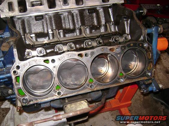 Engine block with pistons visible, showing cylinder walls and gasket