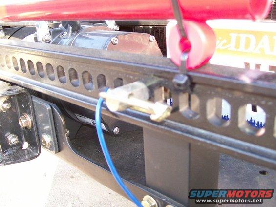 Close-up of a winch motor and mounting bracket with a blue wire attached