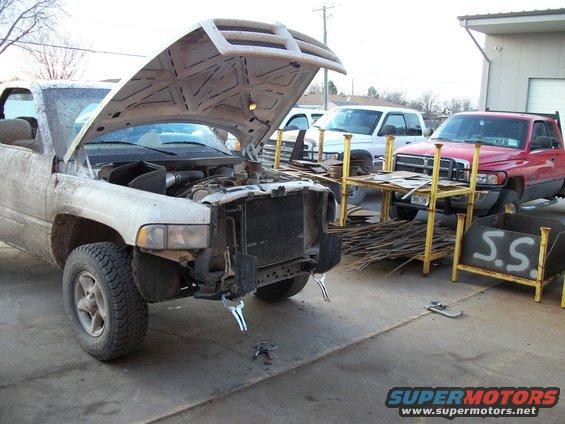 White Dodge Ram pickup truck with hood open, front end disassembled, parked outside