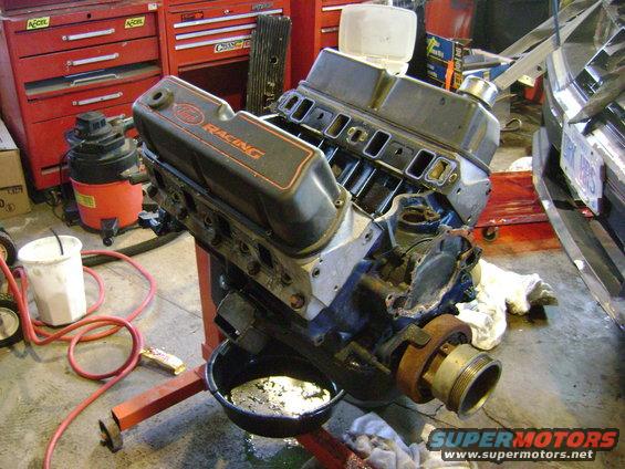 Ford V8 engine with 'RACING' valve covers on an engine stand, with oil pan below