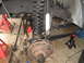 1987 Ford Bronco - Close-up view of the front suspension and steering components of a vehicle, supported by red jack stands.