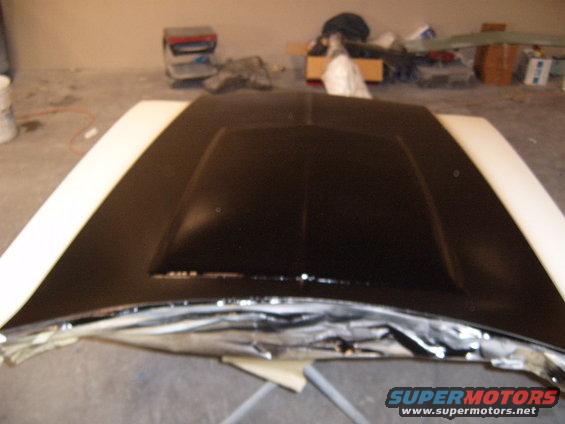 Black car hood with a raised center section, covered in protective material on the edges