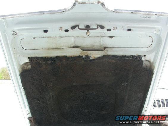 Underside of a white car hood with dark insulation material and latch mechanism