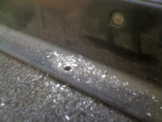 Dark interior panel with debris and a small hole