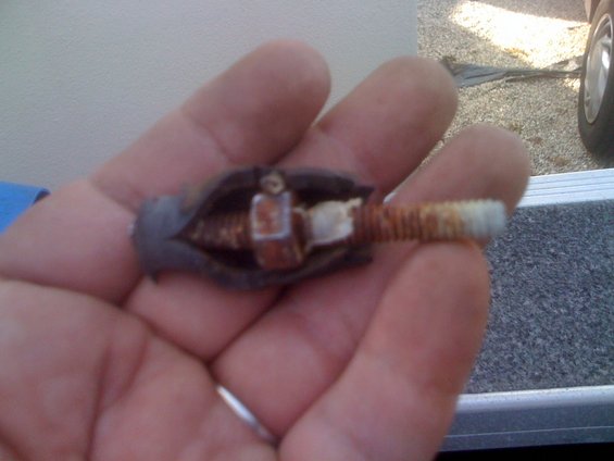 Hand holding a rusty trolling motor part with a threaded shaft