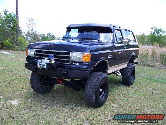 Dark blue Ford Bronco with a winch mounted on the front bumper, lifted with large tires