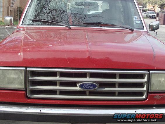 Red Ford Bronco front grille with Ford logo, showing rectangular headlights and chrome bumper