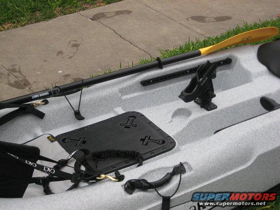 Light gray speckled kayak with black paddle, seat, and accessories on concrete