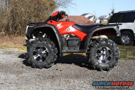 Red ATV with black accents and large tires parked on pavement