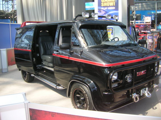 Black GMC van with red stripe, off-road lights, and front brush guard