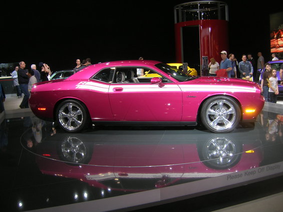 Pink Dodge Challenger with white racing stripes on display