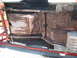 1964 Ford Fairlane - Underside of a car chassis on a rotisserie lift, revealing significant rust and structural wear.