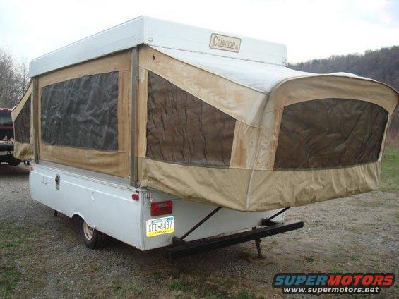 White pop-up camper trailer with tan canvas, viewed from the rear