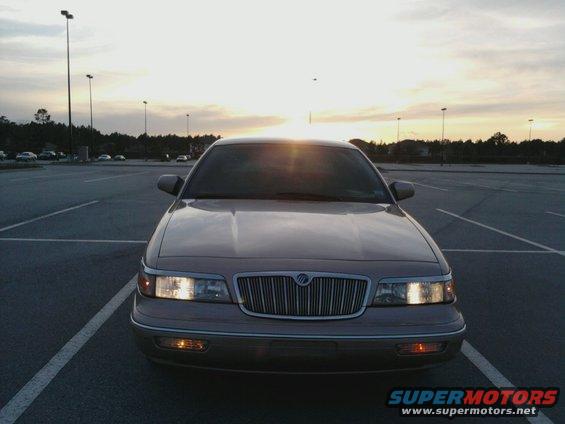 Front view of a tan Mercury Grand Marquis parked in a lot at dusk