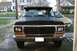 1979 Ford Bronco - Front view of a black 1979 Ford Bronco parked in a driveway with a yellow car behind it.