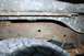 1979 Ford Bronco - The underside of a vehicle shows significant rust on the frame and chassis components, with a tire visible.