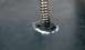 1979 Ford Bronco - A close-up view of a metal spring and its mounting on a dark surface, with visible repair work.