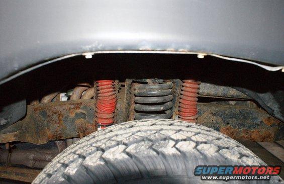 Close-up of front suspension components and tire tread. Red shock absorbers visible