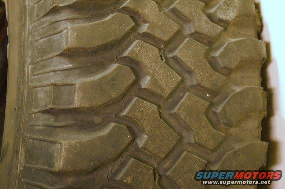 Close-up of a worn tire tread with large, blocky lugs and visible cracking