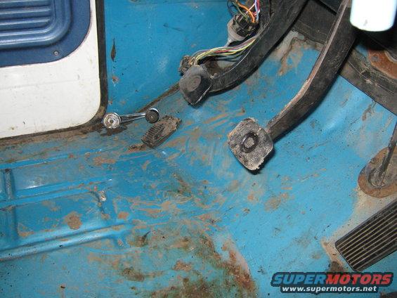 Blue painted metal floor with brake and clutch pedals, window crank, and wiring harness