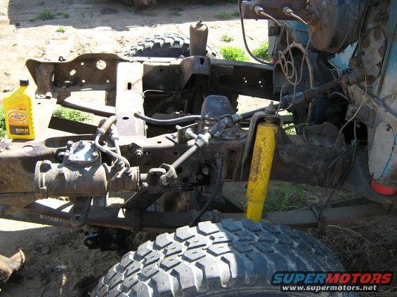 Front suspension and steering components of a truck chassis, with a bottle of oil nearby