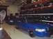 1999 Ford Crown Victoria - Two blue sedans are parked inside a garage, with racks of tires visible on the right.