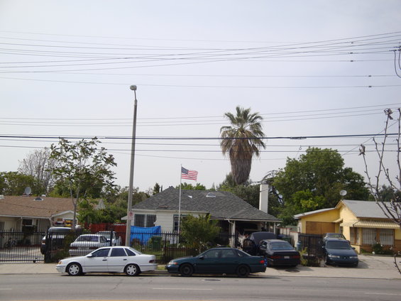Street view of houses and several parked cars under a cloudy sky