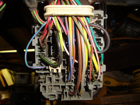 Automotive fuse box with a tangle of colorful wires connected to it