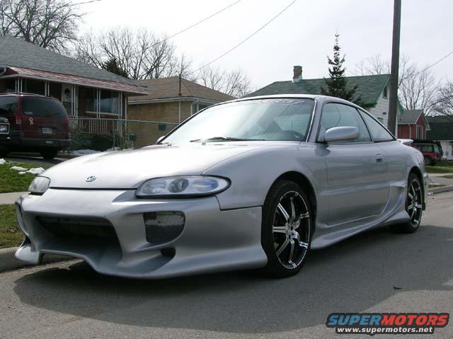 1994 Mazda MX-6 with custom body kit and aftermarket wheels parked on a residential street