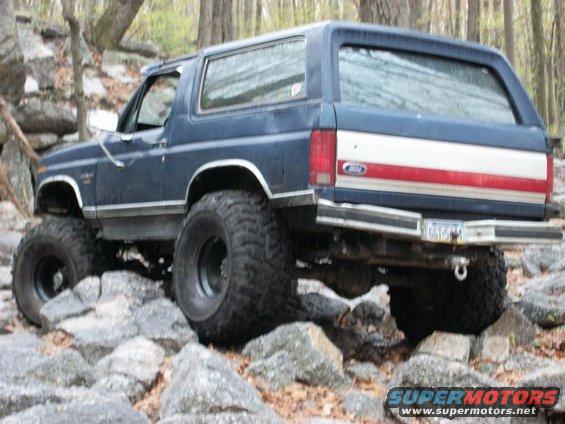 Blue 1986 Ford Bronco with off-road tires on rocks