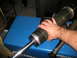 1996 Ford Bronco - Shock absorber assembly with bellows being held over a blue Miller welding machine.