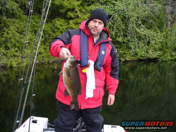 Man holding a fish on a boat with fishing rods