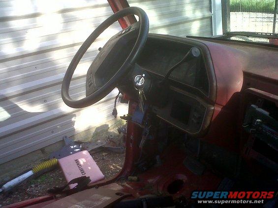 Red car interior with a black steering wheel, dashboard, and keys in the ignition