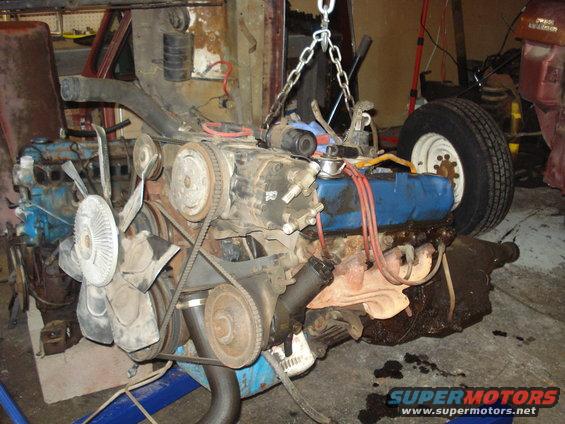 Engine assembly with fan, belts, and carburetor being hoisted by chains