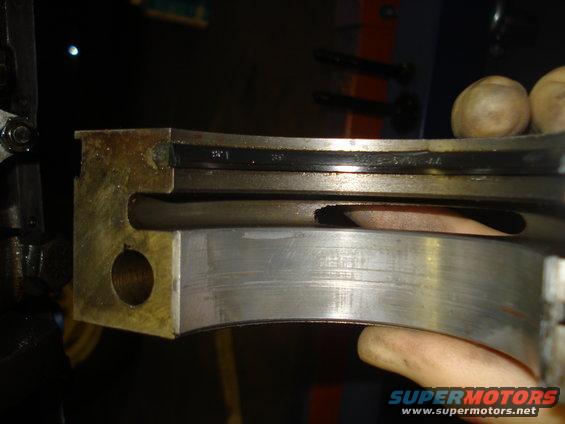 Close-up of a worn engine bearing with visible scoring and a black insert
