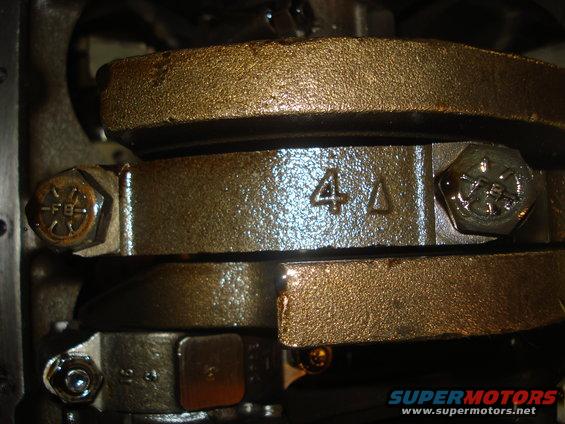 Close-up of engine crankshaft bearing caps with some stamped numbers