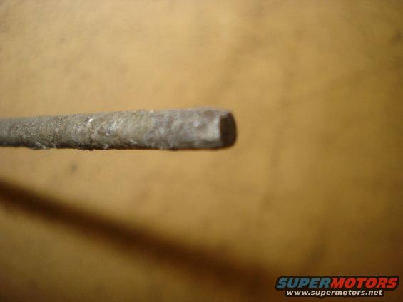 Metal rod with a square end, showing corrosion and texture